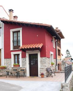 a red building with benches in front of it at El Requexu, apartamentos a 900 m de la playa de Poo in Llanes