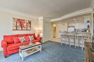 a living room with a red couch and a kitchen at Daytona Beachfront Condo with Ocean View in Daytona Beach