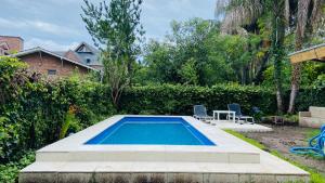 a pool with two chairs and a table in a yard at Lo de Nor in Tigre