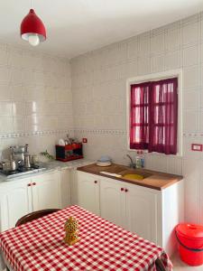 a kitchen with a table with a red and white checkered table cloth at Le bien être in Kelibia +21 photos