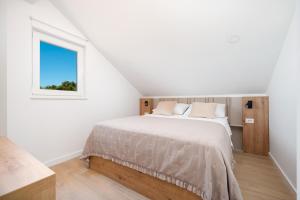 ein weißes Schlafzimmer mit einem Bett und einem Fenster in der Unterkunft Seaside house for families with children Cove Ramascica, Trogir - 23368 in Marina + 13 Fotos