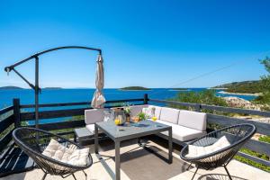 eine Terrasse mit Tisch und Stühlen und dem Meer in der Unterkunft Seaside house for families with children Cove Ramascica, Trogir - 23368 in Marina