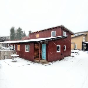 a red building with a blue door in the snow at Los Conejos Bariloche in San Carlos de Bariloche