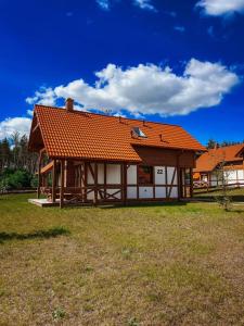 a house with an orange roof on a grass field at Domek na Kaszubach 22-2 - Ostoja Bukowo in Borowy Młyn