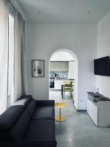 a living room with a black couch and a kitchen at Daddy House in San Giorgio a Cremano