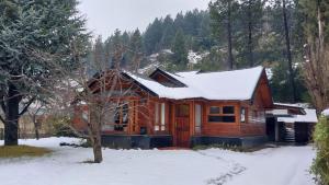 eine Blockhütte mit Schnee auf dem Dach in der Unterkunft Ruca Huenui in San Martín de los Andes