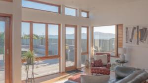 a living room with a couch and a chair and glass doors at Seascapes Beachouse in Paraparaumu
