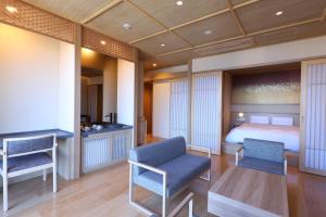une chambre avec un lit et deux chaises dans l'établissement Beppu Hatto Onyado Nono Beppu, à Beppu
