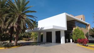Un edificio blanco con palmeras delante. en Hotel Margarita Real Penthouse 6403, en Porlamar