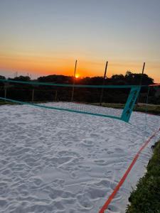a volleyball net in the sand with the sunset in the background at Cabana Pico do Gavião in Andradas