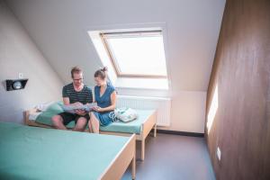 un hombre y una mujer sentados en una cama en una habitación en De Draecke Hostel, en Gante
