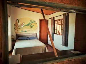 a bedroom with a bed with a painting on the wall at Chalé Angico - Refúgio Namata in Pirenópolis