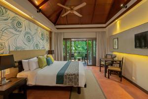 ein Schlafzimmer mit einem Bett und einem Tisch und Stühlen in der Unterkunft Khaolak Merlin Resort in Khao Lak