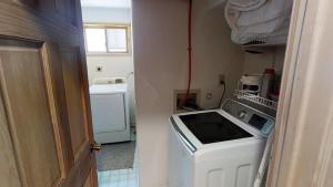 a small kitchen with a washing machine and a washer at Caribel Trail Lodge - Hot Tub - Grill - Satellite - WiFi - Washer - Dryer - Garage Access in Red River
