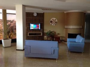 un salon avec deux chaises bleues et une télévision dans l'établissement Hotel Cedro Palace, à São José do Cedro