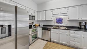 a kitchen with white cabinets and a stainless steel refrigerator at Poolside at DeBordieu Colony in Georgetown