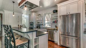 a kitchen with white cabinets and a stainless steel refrigerator at Magnolia in Pawleys Island home by Peace Vacations in Pawleys Island