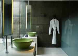 a bathroom with a green bowl sink and a robe at W Bali - Seminyak in Seminyak