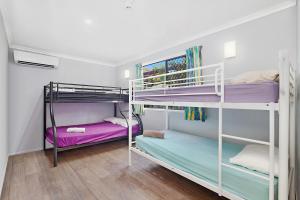 two bunk beds in a room with wooden floors at Gladstone Backpackers in Gladstone
