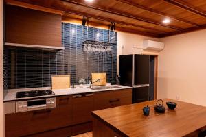a kitchen with wooden cabinets and a wooden table at サウナ付き古民家の宿 和ごろも - Kominka no yado Wagoromo - in Ōtaki