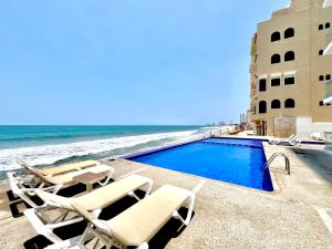 a swimming pool with chairs and the beach at Marina del Sol 402 Vista al Mar in Mazatlán