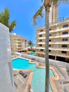 a swimming pool with a palm tree next to a building at Marina del Sol 402 Vista al Mar in Mazatlán
