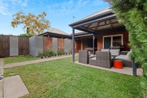 a backyard with a patio with wicker chairs and a gazebo at The Hideaway - Charming Cottage, Entertaining Area in Wagga Wagga