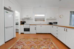 a kitchen with white cabinets and a rug on the floor at The Hideaway - Charming Cottage, Entertaining Area in Wagga Wagga
