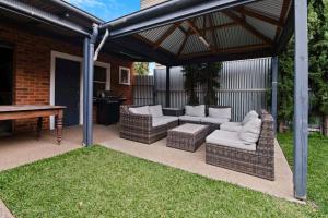 a pergola with two couches and a table at The Hideaway - Charming Cottage, Entertaining Area in Wagga Wagga