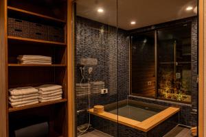 a bathroom with a tub and a glass shower at サウナ付き古民家の宿 和ごろも - Kominka no yado Wagoromo - in Ōtaki