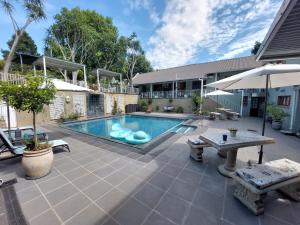 a swimming pool with a table and an umbrella at Apartment 7 On Oakleigh in Pietermaritzburg