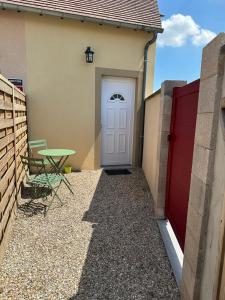a white door on a house with a table at Au cosy in Autheuil-Authouillet