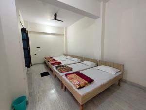 um grupo de camas em um quarto com paredes brancas em Abhishek Guest House em Chamoli