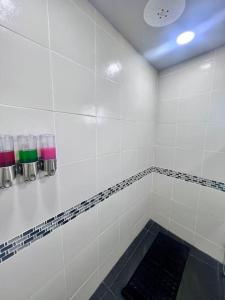 a white tiled shower with a black mat in a bathroom at Apartamento Contemporaneo con TV 85 y cochera privada in Ciudad Victoria +3 photos