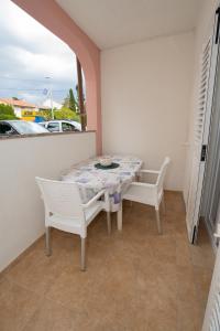 a table and chairs on a balcony with a view of a car at Apartmani Vidušin in Novalja