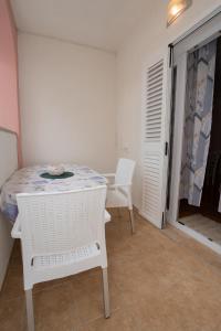 a white table and chairs in a room with a door at Apartmani Vidušin in Novalja