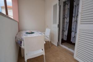 a small room with a table and chairs and a closet at Apartmani Vidušin in Novalja