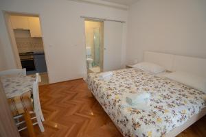 a bedroom with a bed and a table and a kitchen at Apartmani Vidušin in Novalja