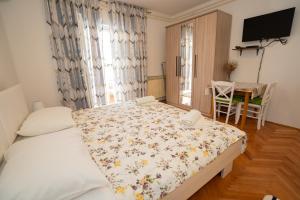 a bedroom with a bed and a table and a television at Apartmani Vidušin in Novalja