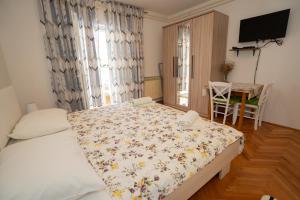 a bedroom with a bed and a table and a television at Apartmani Vidušin in Novalja