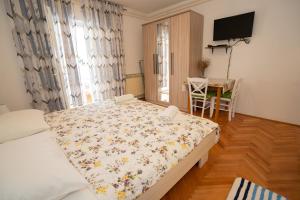 a bedroom with a bed and a table and a television at Apartmani Vidušin in Novalja