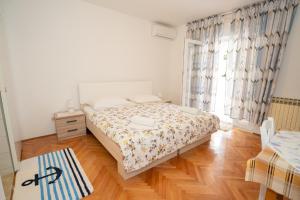 a bedroom with a bed and a large window at Apartmani Vidušin in Novalja