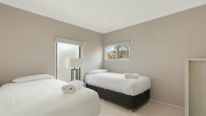 a white room with two beds and a window at Hideaway in Dinner Plain