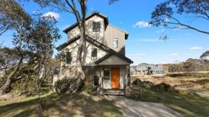 an old house with a orange door in a field at Hideaway in Dinner Plain