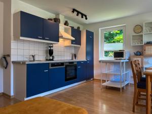 ボルテンハーゲンにあるUrlauberdorf Haus 20aの青いキャビネット、テーブル、窓付きのキッチン