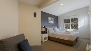 a bedroom with a bed and a couch and a window at Numbawan in Dinner Plain