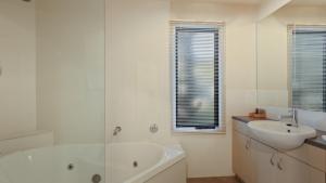 a white bathroom with a tub and a sink at Numbawan in Dinner Plain +7 photos
