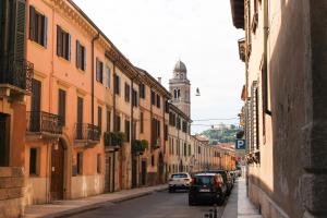Una calle de la ciudad con coches aparcados en la calle. en Giardino Giusti Home, en Verona