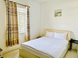 a bedroom with a white bed with a window at Khách sạn Nam Môn in Can Tho