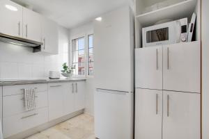 a white kitchen with white cabinets and a refrigerator at Marysol in Caleta De Fuste
